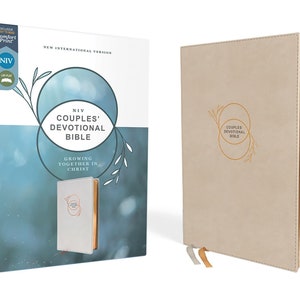 Op de afbeelding: Een beige NIV Couples' Devotional Bible met gouden letters en een bijpassende doos. De doos bevat de tekst "Growing Together in Christ" en "New International Version". Het boek heeft twee linten als bladwijzers.