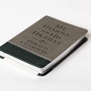 Può includere: Un diario rilegato in pelle grigia con il titolo "My Utmost for His Highest" e l'autore "Oswald Chambers" in rilievo sulla copertina.