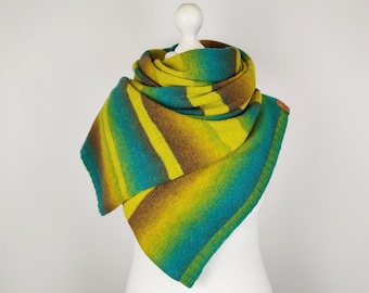 May include: A colorful, striped shawl in shades of teal, yellow, and brown, displayed on a white mannequin. The knitted shawl features a triangular shape and a small, round, brown leather tag.