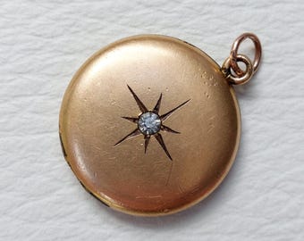 May include: A gold locket with a single diamond set in a starburst design.
