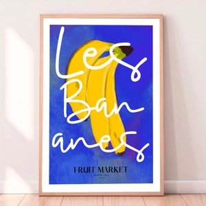 May include: A blue poster with the text "Les Bananes" in white cursive writing. A bunch of yellow bananas are in the center of the poster. The text "Fruit Market" is at the bottom of the poster.