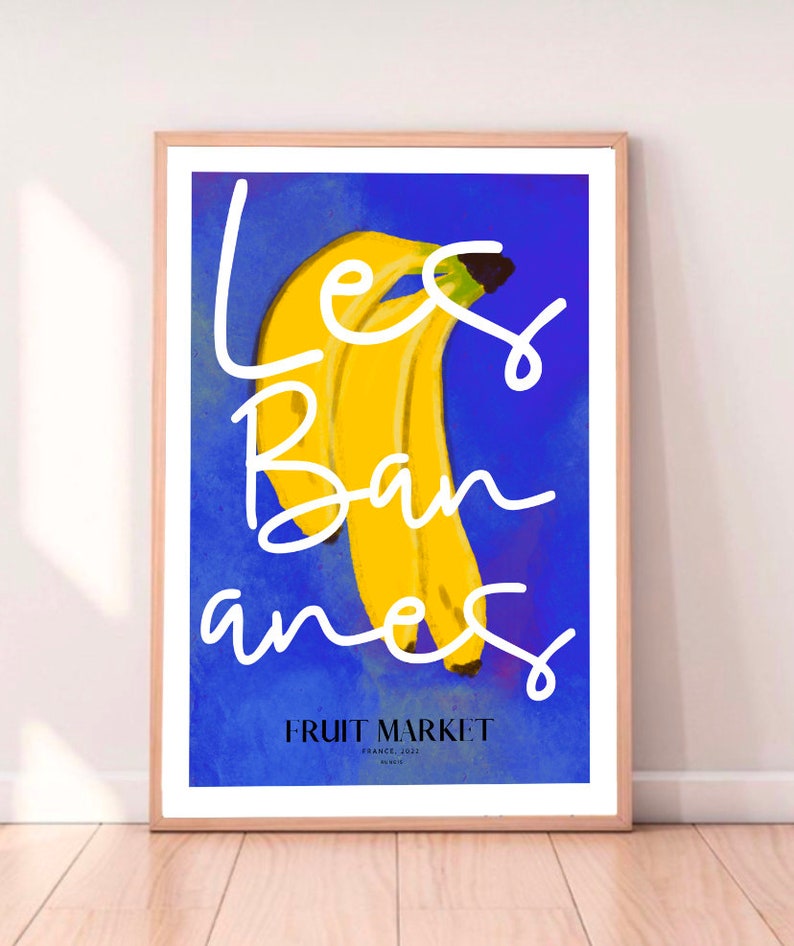 May include: A blue poster with the text "Les Bananes" in white cursive writing. A bunch of yellow bananas are in the center of the poster. The text "Fruit Market" is at the bottom of the poster.