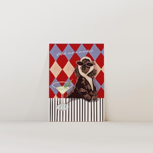 Peut inclure: Impression artistique fantaisiste avec un chien marron portant des lunettes de soleil et une écharpe, avec un verre à martini. Le fond présente un motif de losanges rouges et bleus, avec le texte "fetch me a martini".