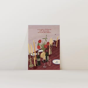 Puede incluir: Ilustración de una mesa con botellas de vino, copas, platos, velas y un arreglo floral. El texto "I've seen it dance with friends around the table" está escrito en rojo. La mesa es de color rojo oscuro.