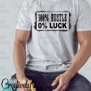 May include: A white t-shirt with a black graphic that reads "100% Hustle 0% Luck". The graphic is in a distressed, spray-painted style.