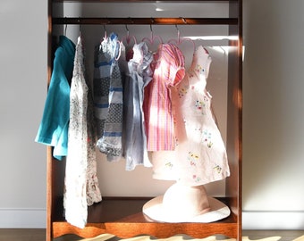 Ein Montessori-Kleiderschrank, dunkelbrauner, gewölbter Kleiderständer für Kleinkinder, Aufbewahrung für Kinderkleidung im Boho-Stil