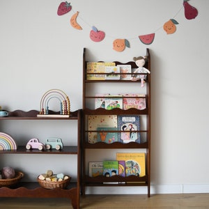 a wall mounted bookcase in dark brown stain with a wavy decor