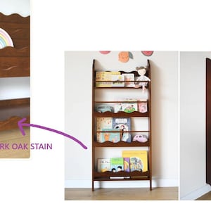 May include: A dark oak stained wooden bookshelf with a scalloped edge design. The bookshelf is filled with children's books and a small doll. The bookshelf is designed to hold books and display them.