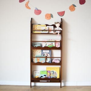 a wall mounted bookcase in dark brown stain with a wavy decor