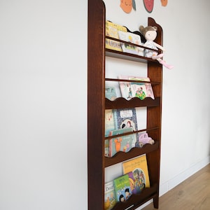 a wall mounted bookcase in dark brown stain with a wavy decor