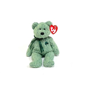 May include: Green plush teddy bear with a green shamrock on its chest and a red Ty heart tag.