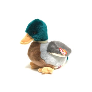Puede incluir: Un juguete de peluche de pato silvestre verde, marrón y gris con una etiqueta de Beanie Baby roja y blanca.