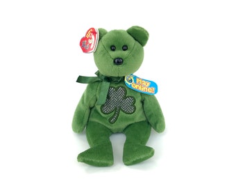 Peut inclure: Ours en peluche vert avec un trèfle sur la poitrine. L'ours a des yeux noirs et un nez noir. L'ours porte un ruban vert autour du cou. L'ours a une étiquette qui dit "Jouer en ligne !"