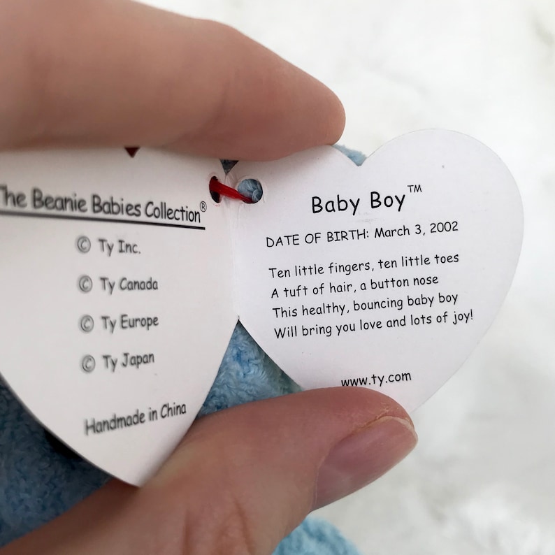 May include: A heart-shaped tag with the words "Baby Boy" and "Date of Birth: March 3, 2002". The tag also includes a poem about a baby boy with ten fingers and toes, a tuft of hair, and a button nose. The tag is made in China and has the website www.ty.com printed on it.