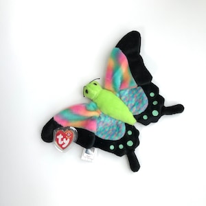 May include: A green, black, pink and blue butterfly Beanie Baby with a Ty tag. The butterfly has a green head and black wings with colourful spots.
