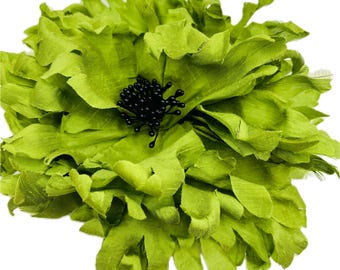 Peut inclure: Une grande fleur en tissu vert lime avec un centre noir. La fleur est composée de nombreuses couches de tissu et a un aspect plissé.