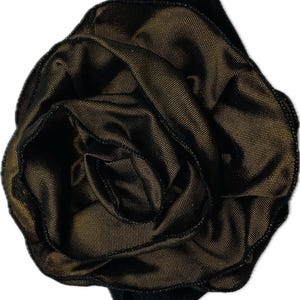 May include: A black and gold fabric flower, possibly a hair accessory or decorative element. The flower has multiple layers of petals, creating a full, textured appearance. The gold color has a subtle sheen, adding depth to the design.