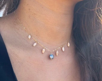 May include: A gold chain necklace with a large black pearl pendant and smaller white pearl accents.