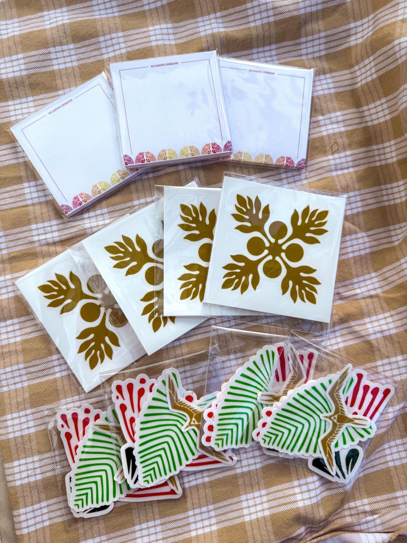 May include: A set of stickers featuring a gold floral design and a green and red geometric design. The stickers are packaged in clear plastic bags.
