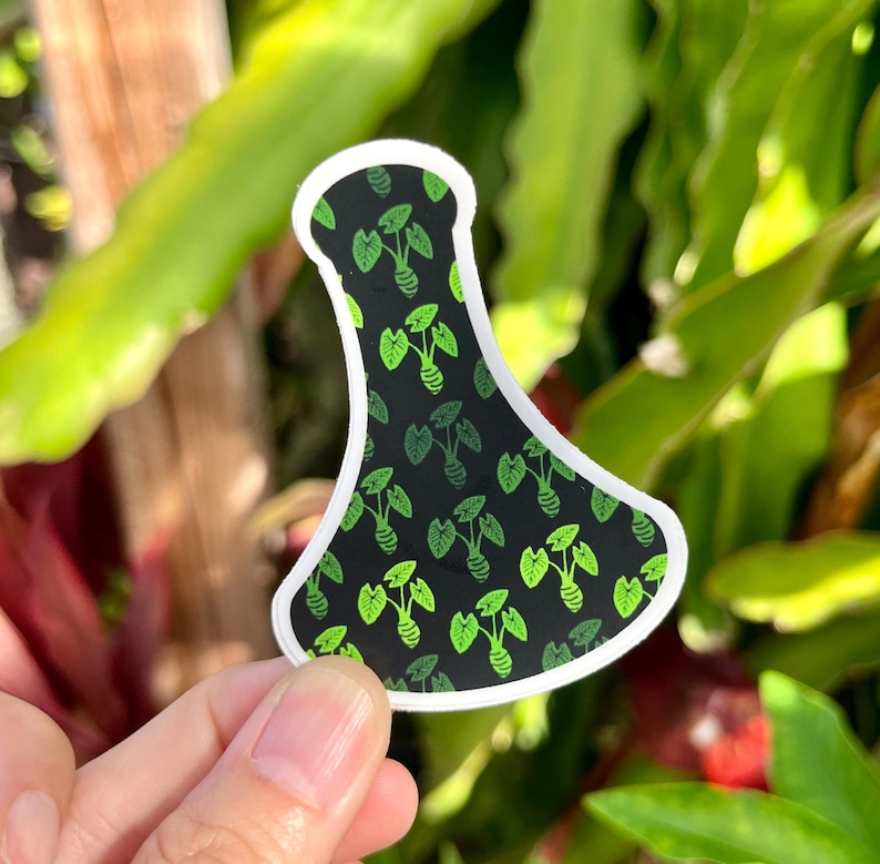 May include: A black and green vinyl sticker of a bottle with a leafy pattern. The sticker is shaped like a bottle and has a white outline.