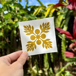 May include: A gold vinyl sticker with a traditional Hawaiian flower design. The sticker is on a white background.