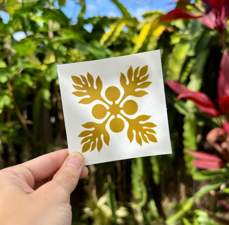 May include: A gold vinyl sticker with a traditional Hawaiian flower design. The sticker is on a white background.