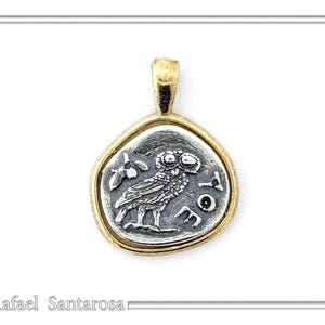 May include: A gold chain necklace with a silver pendant featuring a detailed image of an owl. The pendant is shaped like a coin with a raised edge and the words 'ATHENA' inscribed around the owl.