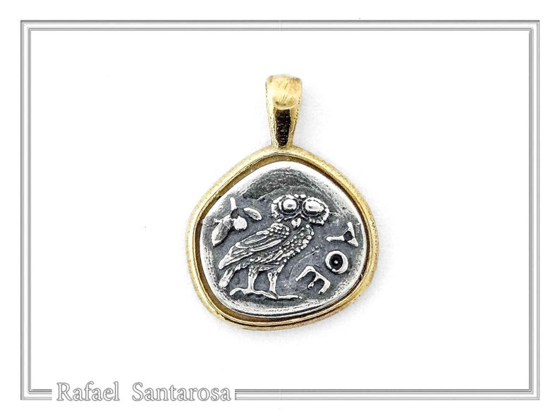 May include: A gold chain necklace with a silver pendant featuring a detailed image of an owl. The pendant is shaped like a coin with a raised edge and the words 'ATHENA' inscribed around the owl.
