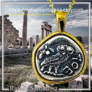 May include: A gold-toned pendant featuring a circular coin design with a relief of an owl and the Greek letters AOE. The pendant is suspended from a gold-toned chain. The text https://rafaelsantarosa.etsy.com and Rafael Santarosa are visible.