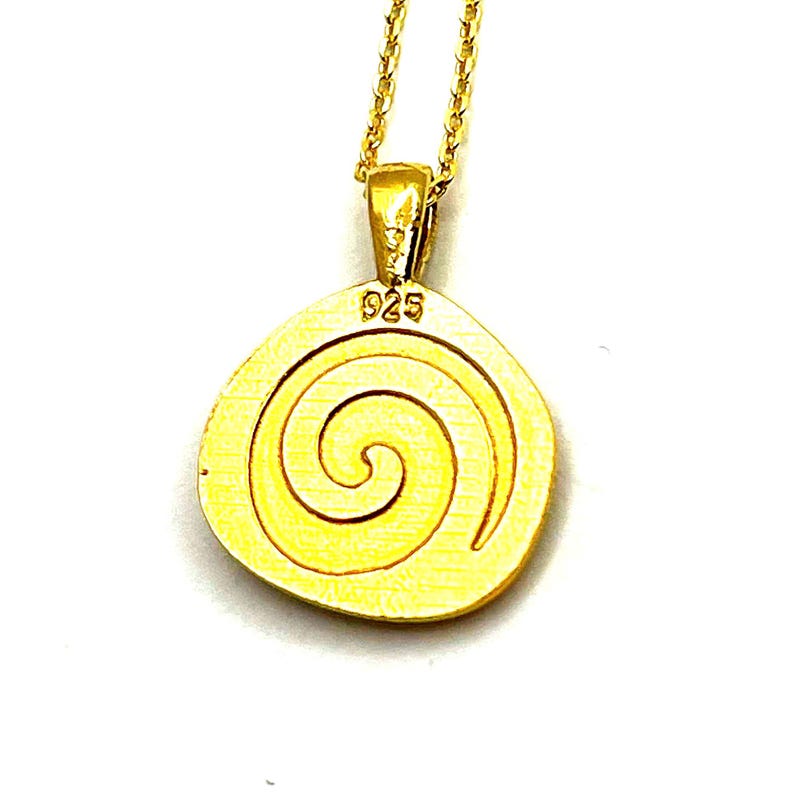 May include: A gold-toned pendant necklace featuring a circular charm with an embossed spiral design. The pendant is suspended from a delicate gold-toned chain and displays the text 925 clearly stamped at the top, indicating the metal purity.