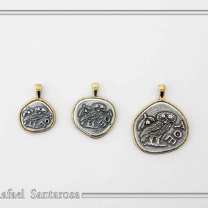May include: Three silver-toned pendants of varying sizes, each featuring an embossed owl design and the Greek letters AOE. Each pendant is framed by a gold-toned border and includes a small gold-toned bail at the top for attachment to a chain.