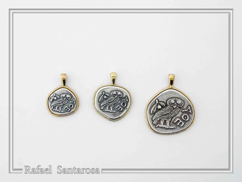 May include: Three silver-toned pendants of varying sizes, each featuring an embossed owl design and the Greek letters AOE. Each pendant is framed by a gold-toned border and includes a small gold-toned bail at the top for attachment to a chain.