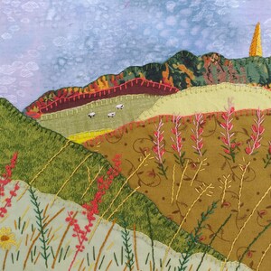 May include: A colourful embroidered landscape with a brown, green and yellow hillside, a blue sky with white clouds, and a tall, thin, yellow structure in the background.
