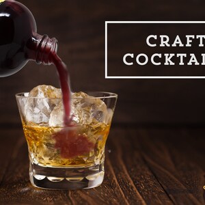 May include: A glass of amber liquid with ice cubes is being poured with a dark red liquid from a bottle labeled "Shivelight Premium Beverage Co.". The text "CRAFT COCKTAILS" is displayed in a white rectangle on a dark brown background.