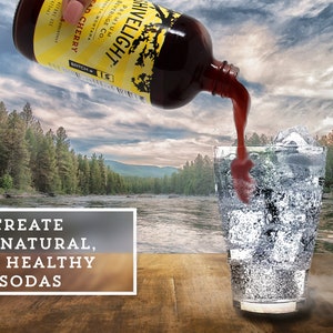 May include: A glass bottle with a yellow label that reads "Hivelight Premium Beverage Co. Wild Cherry" is being poured into a glass with ice. The glass is on a wooden surface with a river and trees in the background. The text "Create All Natural, Gut Healthy Sodas" is on a white rectangle in the foreground.