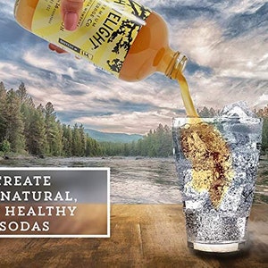 May include: A glass bottle of Shivelight Premium Beverage Co. ginger soda being poured into a glass with ice. The bottle is labeled "Shivelight" and "Premium Beverage Co." The text "Create All Natural, Gut Healthy Sodas" is on a wooden surface in front of the glass.