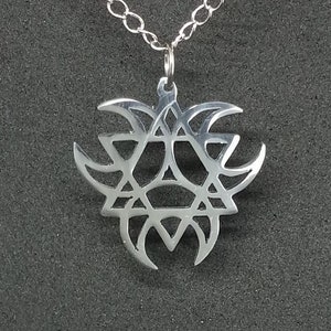Puede incluir: Un collar de plata con un colgante geométrico. El colgante es un diseño complejo de triángulos y círculos superpuestos.