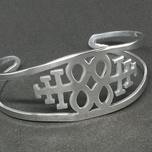 May include: A silver metal bracelet with a cutout design featuring the word "HOPE" repeated three times.