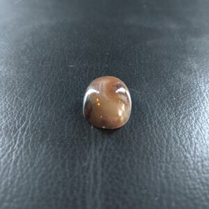 May include: A smooth, oval-shaped agate stone with brown, white, and gray swirling patterns.