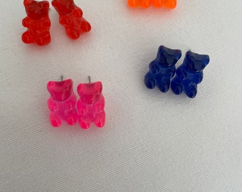 May include: Four pairs of gummy bear shaped earrings in red, orange, pink, and blue.