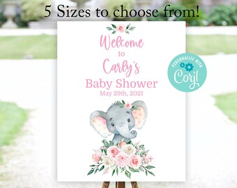 May include: A white sign with a pink and gray elephant illustration and floral accents. The sign reads "Welcome to Carly's Baby Shower May 29th, 2021". A teal circle with the text "PERSONALIZE WITH Coryl" is in the top right corner.