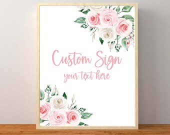 May include: Printable sign with a floral design featuring pink and white roses and green leaves. The text "Custom Sign" and "your text here" is written in pink.