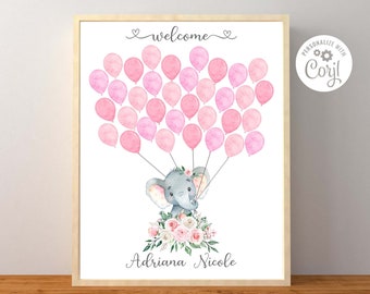 May include: A white framed print with a watercolor illustration of a gray elephant holding pink balloons. The elephant is wearing a floral crown and is surrounded by pink flowers. The text "welcome" is at the top of the print, and the text "Adriana Nicole" is at the bottom.