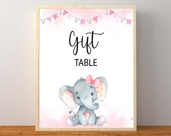 May include: A pink and white printable sign with the text "Gift Table" and a watercolor illustration of a gray elephant with pink polka dots and a pink bow.