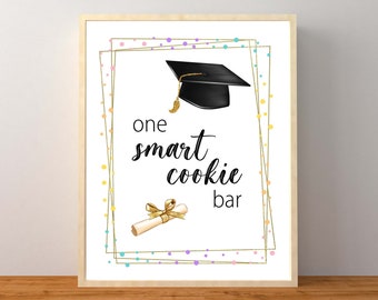 May include: A white sign with a gold frame and colorful confetti. The sign says "one smart cookie bar" and features a black graduation cap and a gold diploma.