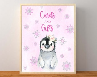 May include: A pink and white printable sign featuring a penguin wearing a flower crown. The sign reads "Cards and Gifts" with snowflakes in the background.