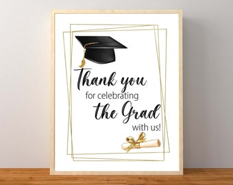 May include: A white sign with a gold frame and a black graduation cap and diploma. The sign says "Thank you for celebrating the Grad with us!"