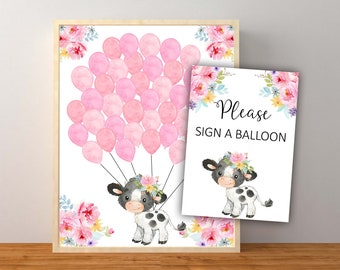 May include: A printable sign for a baby shower with a cute cartoon cow holding pink balloons. The sign says "Please sign a balloon".