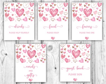 May include: Five printable signs with pink and gold hearts and text. The signs read "drinks please help yourself", "food please enjoy", "favors please take one", "cards and gifts", and "guest book please sign".