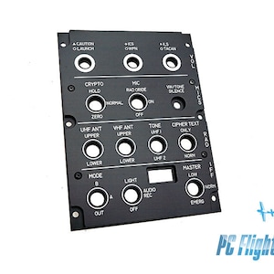 Może przedstawiać: Czarny panel sterowania z różnymi przełącznikami i przyciskami oznaczonymi tekstem, takim jak "Caution Launch", "Crypto Hold", "Mic Rad Override", "VHF Ant Upper", "UHF Ant Upper", "Tone UHF", "Cipher Text Only", "Mode", "Light", "Audio Rec", "Master Low", "Norm", "Emerg" i "PC Flights".